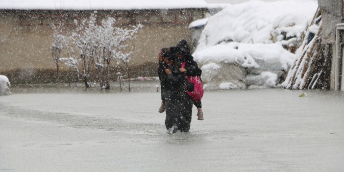 Evinin önünde biriken su nedeniyle çocuklarını sırtında taşıyor