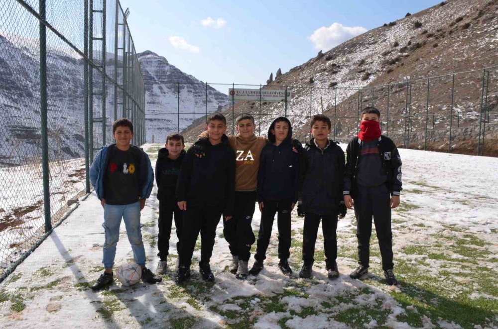 Çocuklar futbol aşkına karlı yolları aşıp halı sahada top oynuyor