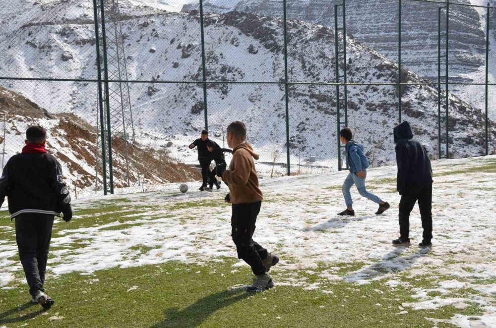 Çocuklar futbol aşkına karlı yolları aşıp halı sahada top oynuyor