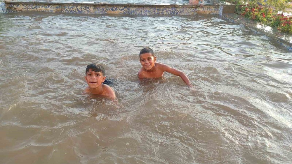 Urfa’da sıcaktan bunalan çocuklar süs havuzunda serinledi