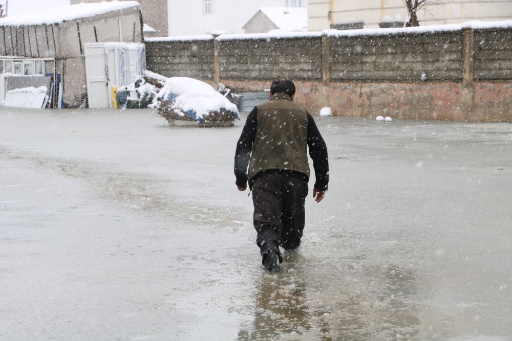 Evinin önünde biriken su nedeniyle çocuklarını sırtında taşıyor