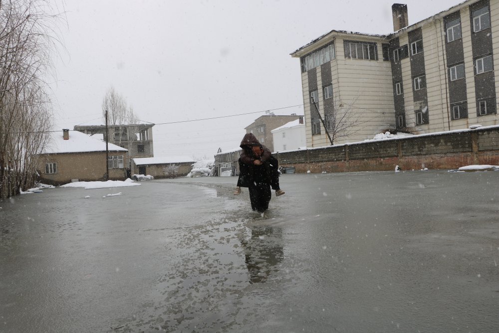 Evinin önünde biriken su nedeniyle çocuklarını sırtında taşıyor