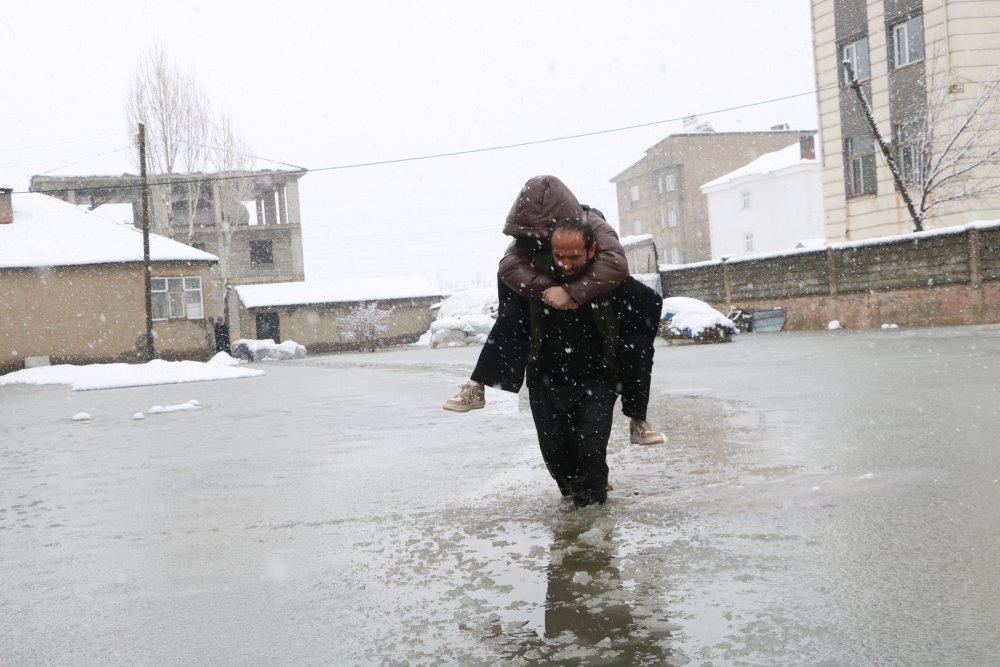 Evinin önünde biriken su nedeniyle çocuklarını sırtında taşıyor
